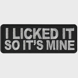 May include: Black rectangular patch with the embroidered phrase "I LICKED IT SO IT'S MINE" in white, bold, capital letters. The patch has rounded corners and a black border.