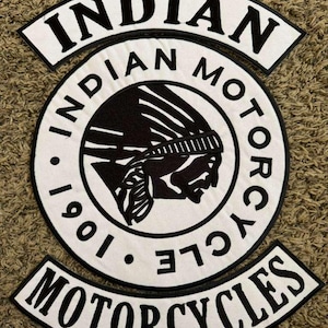 May include: A white and black embroidered patch featuring the words "INDIAN MOTORCYCLES" and a Native American profile. The patch includes the year "1901" and is circular with a curved top and bottom.