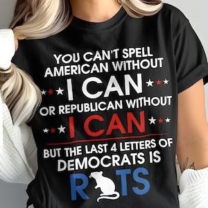 May include: Black t-shirt with white text: "YOU CAN'T SPELL AMERICAN WITHOUT I CAN" and "OR REPUBLICAN WITHOUT I CAN". The text "I CAN" is in red. The text "BUT THE LAST 4 LETTERS OF DEMOCRATS IS RATS" is also on the shirt.