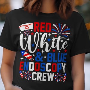May include: Black t-shirt with the words "Red White & Blue Endoscopy Crew" in red, white, and blue. The design includes a nurse's cap, fireworks, and stars, celebrating a patriotic theme.