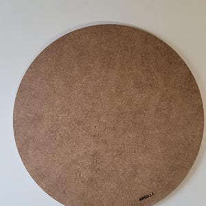 Peut inclure: Une surface de bricolage ronde en bois non finie. La surface est de couleur brun clair et a un aspect texturé. Le mot "ARGILLA" est imprimé en noir dans le coin inférieur droit. Sur fond blanc.