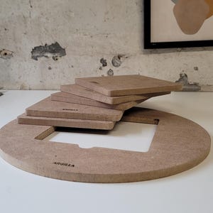 Peut inclure: Ensemble de pièces de bricolage en bois marron clair. L'ensemble comprend une grande pièce circulaire avec une découpe, plusieurs pièces carrées et le mot "ARGILLA" imprimé.