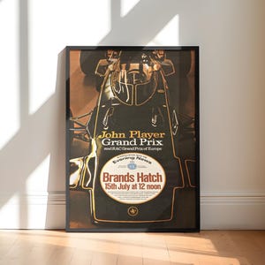 May include: Framed vintage poster for the John Player Grand Prix at Brands Hatch. The poster features a top-down view of a race car in black and gold, with event details including the date, July 15th, and time, 12 noon.