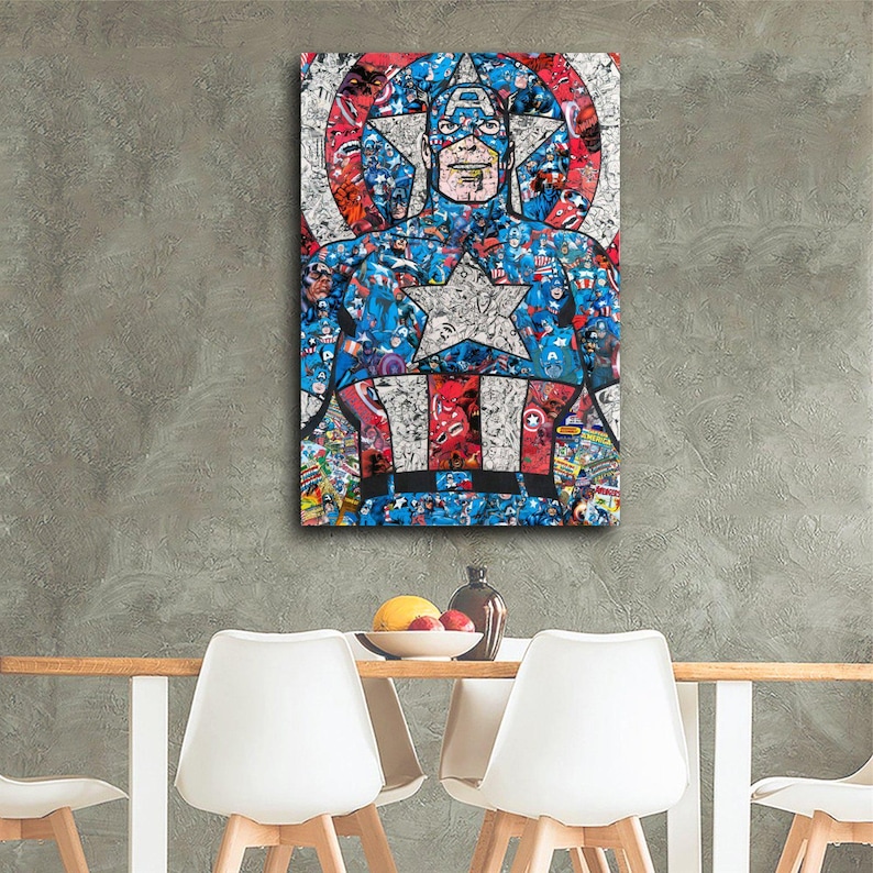 May include: A framed Captain America artwork. The artwork features a collage of comic book images in red, white, and blue, forming the iconic superhero's likeness. The image is displayed on a gray wall above a table with white chairs.