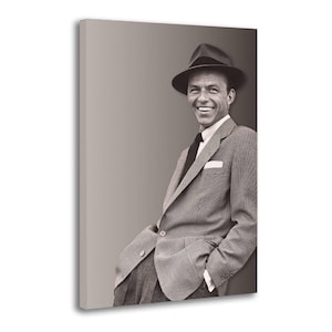 May include: Black and white portrait of a man in a suit and fedora hat. The man is smiling and leaning against a wall. The suit has a patterned design, and a pocket square is visible.
