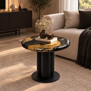 Puede incluir: Una mesa auxiliar redonda con una superficie negra brillante y detalles dorados en espiral. La mesa se apoya en una base central compuesta por tres columnas cilíndricas de color negro mate sobre una placa circular negra en el suelo.