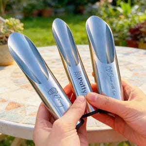 May include: Three stainless steel garden scoops with long, curved heads. Each scoop has a different inscription: "Tierney" with a cactus, "Patty", and "Grow with love". The scoops are held by a person.