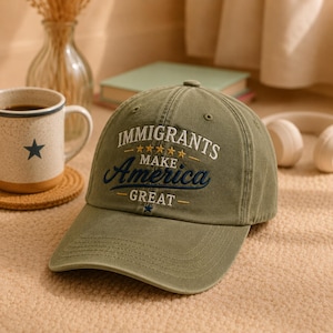 May include: Olive green baseball cap with the embroidered text "IMMIGRANTS MAKE America GREAT" in white and navy blue. The cap has a curved brim and a classic six-panel design. A casual accessory for everyday wear.