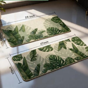 May include: Two rectangular floor mats with a tropical leaf design. The larger mat is 47 inches long and 17 inches wide, while the smaller one is 29 inches long and 1 inch wide. The mats feature green and white leaves.