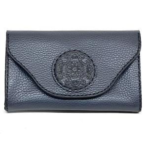 May include: A white ceramic mug with a black handle and the text "But First, Coffee" in a bold, black font. The mug is set against a blurred background, suggesting a cozy setting.