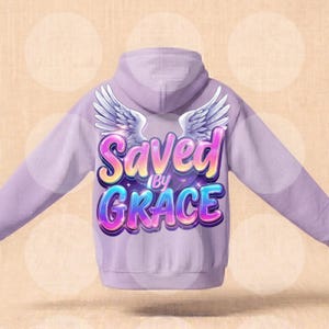 Puede incluir: Sudadera con capucha de color lila claro con la frase "Saved by Grace" en una fuente colorida y de burbujas. El diseño incluye alas de ángel blancas sobre el texto. La sudadera tiene capucha y mangas largas.