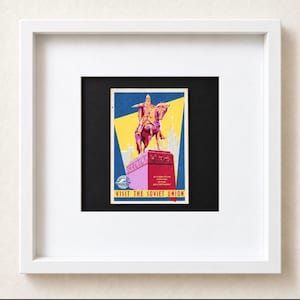 May include: A framed vintage travel poster featuring a stylized illustration of a rider on horseback atop a pedestal. The artwork uses a palette of blue, yellow, and magenta. The text reads "VISIT THE SOVIET UNION" in yellow letters at the bottom.