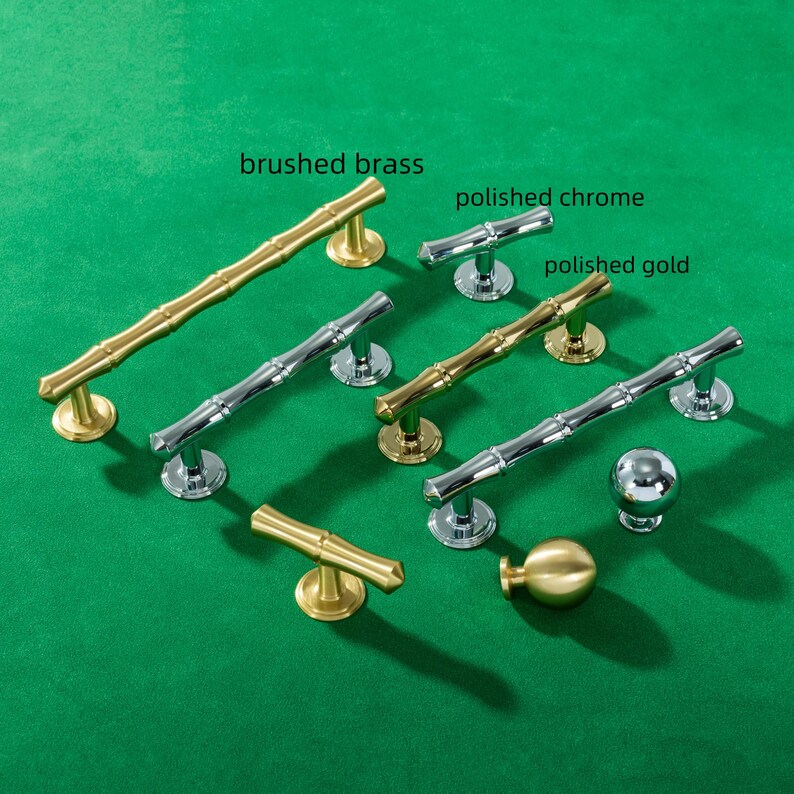 May include: Various cabinet handles and knobs in brushed brass, polished chrome, and polished gold. The hardware includes bamboo-style handles and round knobs, displayed on a green surface. The text "brushed brass", "polished chrome", and "polished gold" are visible.