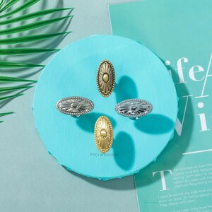 K&ouml;nnte beinhalten: Vier ovale Schrankkn&ouml;pfe in Gold- und Silbert&ouml;nen sind auf einer hellblauen Oberfl&auml;che angeordnet. Die Kn&ouml;pfe haben ein Sonnenstrahl-Design. Der Text "PYCraftGoods" ist auf der Oberfl&auml;che sichtbar.