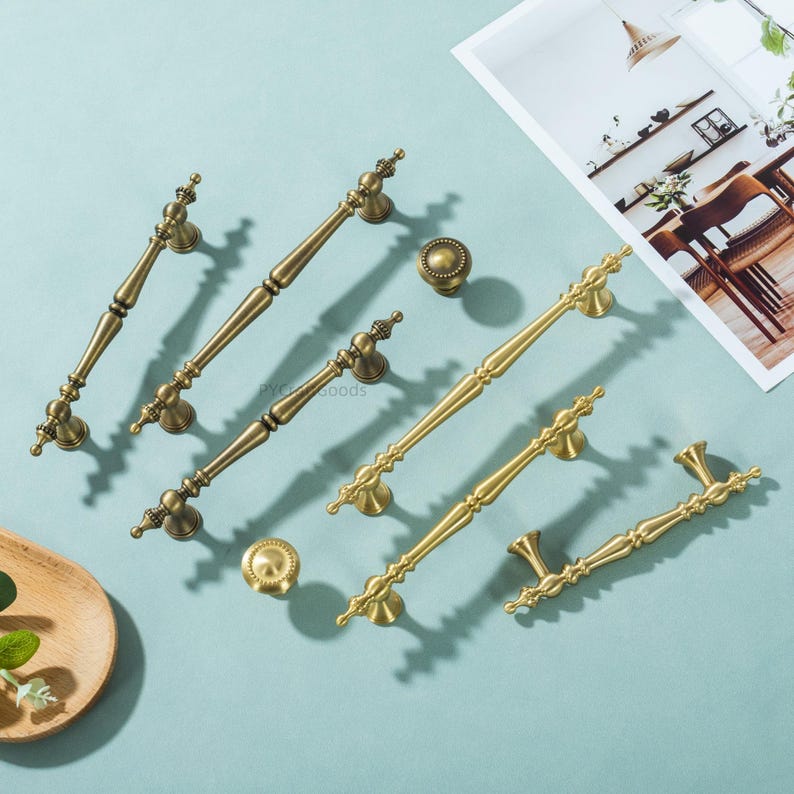 Peut inclure: Divers mod&egrave;les de poign&eacute;es et boutons de meubles en laiton antique. Le mat&eacute;riel pr&eacute;sente des d&eacute;tails orn&eacute;s et une finition vieillie et chaleureuse. Les poign&eacute;es sont de tailles et de styles vari&eacute;s, pour diff&eacute;rents meubles.