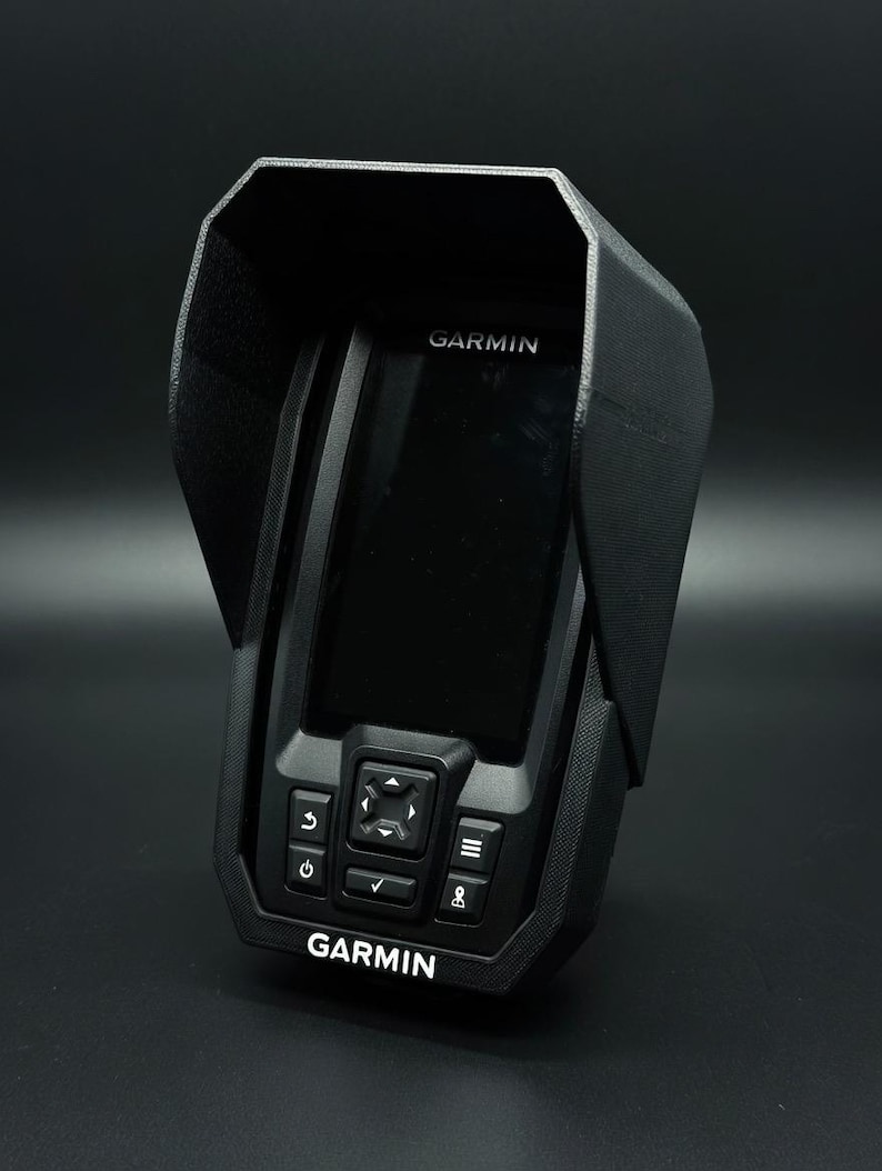 Puede incluir: Un buscador de peces Garmin negro con una cubierta protectora. El dispositivo tiene una pantalla, botones y el logotipo de Garmin en blanco. La cubierta tiene una superficie texturizada y una extensi&oacute;n tipo visera.