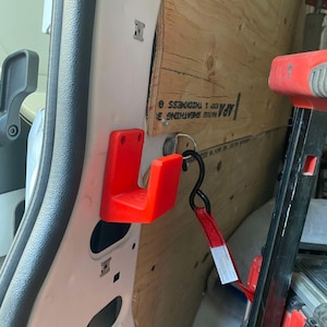 May include: A white ceramic mug with a black handle and the text "But First, Coffee" in a bold, black font. The mug is set against a blurred background, suggesting a cozy setting.