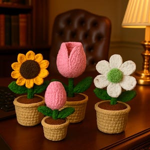 May include: A selection of handmade crochet flowers in small woven pots. The flowers include a yellow sunflower, a pink tulip, a pink bud, and a white daisy with a green centre. The pots are beige and filled with brown material.