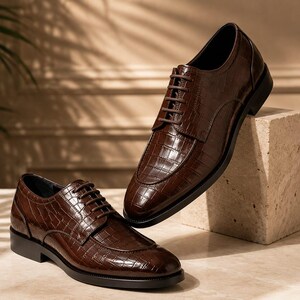 May include: A pair of dark brown lace-up dress shoes featuring a glossy crocodile-embossed leather texture. The shoes have a rounded toe, a low stacked heel, and matching dark brown laces, showcasing a structured silhouette and polished finish.