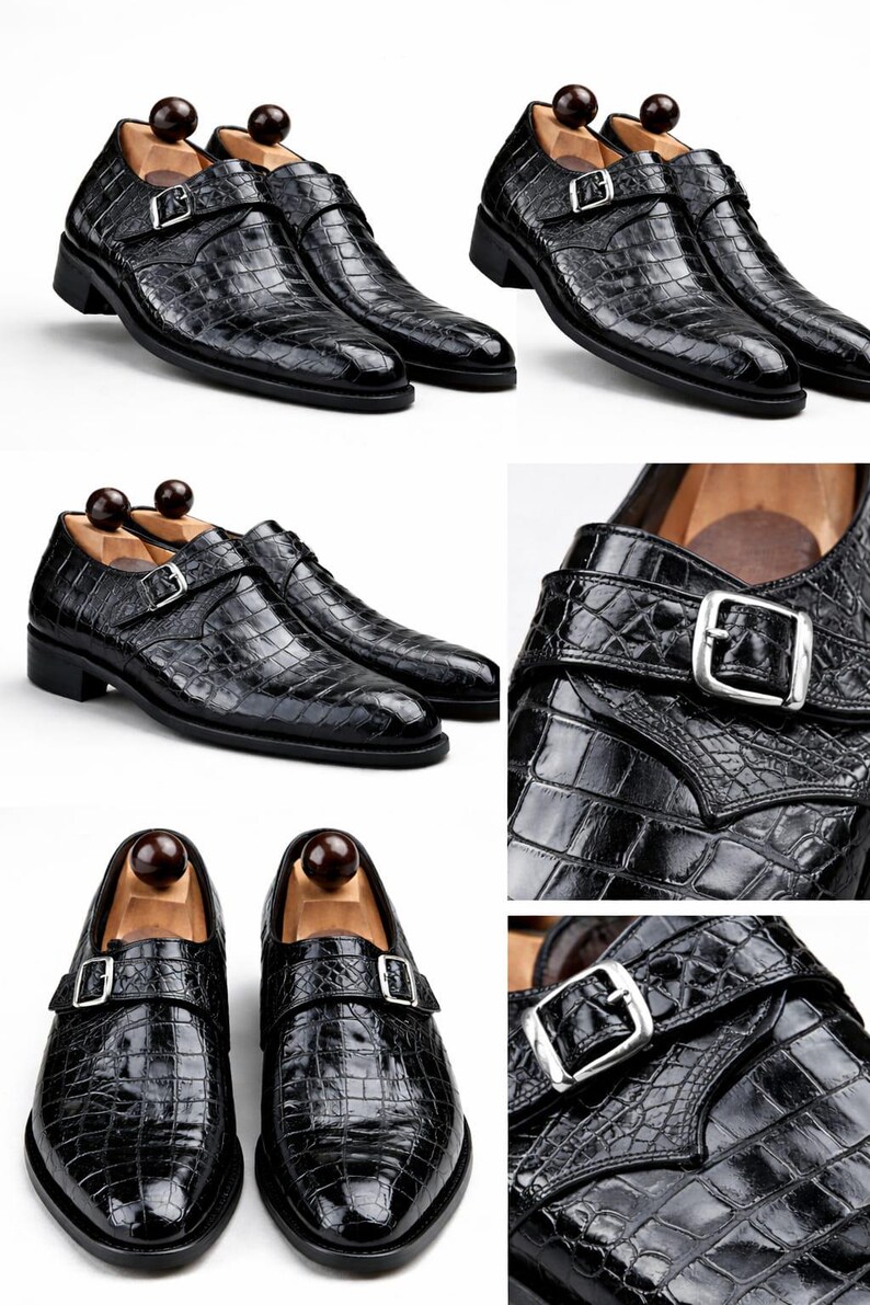 Op de afbeelding: Zwarte leren monk strap schoenen met een krokodillenstructuur. De schoenen hebben een zilveren gespsluiting. De schoenen worden op een witte achtergrond gepresenteerd. Er zitten schoenspanners in.