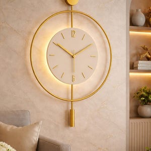 May include: A modern wall clock with a gold-colored frame and hands. The clock face is a light cream color with gold-colored hour markers. The clock is mounted on a textured wall. The clock's design includes a circular frame and a pendulum.