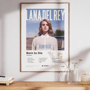 May include: A rectangular wall poster featuring the Lana Del Rey Born to Die album cover. The design includes a portrait of a person in a white collared shirt against a blue sky, with the text Lana Del Rey and Born to Die, plus a tracklist.