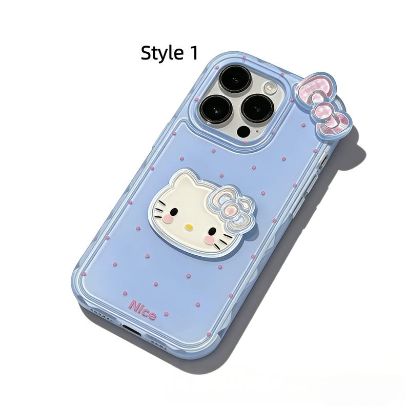 May include: A light blue phone case with a Hello Kitty design. The case has a clear border and features a 3D Hello Kitty face and bow, along with pink polka dots. The word "Nice" is printed on the bottom.