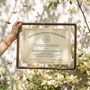 Pode incluir: Uma moldura flutuante retangular de madeira escura contendo um diploma na cor creme com texto preto que diz INSTITUTIO UNIVERSITATIS MAXIMAE, INSTITUTIO GENERICA HAC LITTERA TESTATUR ET CONFIRMAT DONARE HONOREM GRATI UPON STUDENTIS NOMEN HIC ADSCRIBITUR.