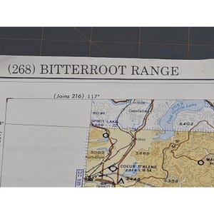 May include: A detailed map section featuring the text "(268) BITTERROOT RANGE" at the top. The map includes geographical features, elevation markers, and place names like Spirit Lake and Coeur d'Alene. The map is tan and brown.