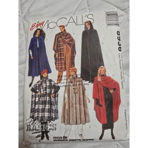 May include: A sewing pattern envelope featuring illustrations of capes in various styles. The capes are shown in different colors and patterns, including solid blue, plaid, and solid black. The envelope has the text "Easy McCall's" and "Basics".