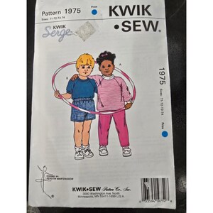 May include: A vintage Kwik Sew sewing pattern, pattern 1975, featuring illustrations of two children. The pattern includes the text "Serge" and "KWIK SEW." The pattern is for sizes T1-T2-T3-T4. The pattern is from Kwik Sew Pattern Co., Inc.