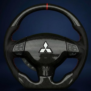 Puede incluir: Un volante de fibra de carbono con costuras rojas y una franja roja en la parte superior. El volante presenta un logotipo de Mitsubishi y botones de control integrados. El diseño incluye secciones de cuero perforado para el agarre y un indicador de airbag.
