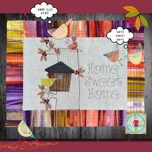 Op de afbeelding: Borduurwerk met een vogelhuisje, vogels en de tekst "Home Sweet Home" op een witte linnen achtergrond. Het ontwerp is omgeven door een kleurrijke stoffen rand.