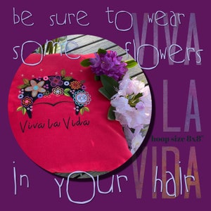 May include: Red fabric with embroidered flowers and the text "Viva la Vida" in black. The fabric is surrounded by pink and white flowers. The text "be sure to wear some flowers in your hair" is written in a circle around the fabric. The text "LA VIDA" is written in a circle below the fabric. The text "hoop size 8x8" is written below the text "LA VIDA".