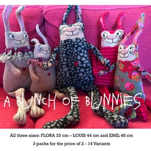 May include: A bunch of colorful handmade bunny plushes in various sizes, sitting on a pink couch. The bunnies are made from knitted fabric and have embroidered faces. The text "A bunch of bunnies" is written in white across the bottom of the image. The text "All three sizes: FLORA 33 cm - LOUIS 44 cm and EMIL 48 cm" is written below the image. The text "3 packs for the price of 2 - 14 Variants" is written below the first line of text.