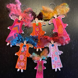 Puede incluir: Siete adornos de &aacute;ngel de fieltro hechos a mano con tela estampada de colores y pelo de lana. Los &aacute;ngeles son todos de diferentes colores y patrones, y todos cuelgan de una cuerda.