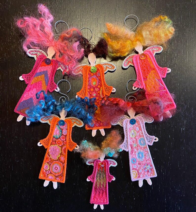 Puede incluir: Siete adornos de &aacute;ngel de fieltro hechos a mano con tela estampada de colores y pelo de lana. Los &aacute;ngeles son todos de diferentes colores y patrones, y todos cuelgan de una cuerda.