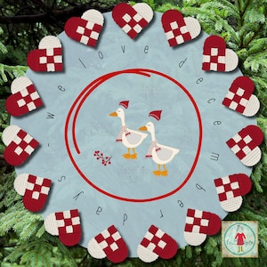 May include: A blue and white background with the words "We love December" spelled out in red letters.  The letters are surrounded by red and white crocheted hearts.  Two white geese with red hats are in the center of the image.  The geese are standing on a red circle with the words "Merry Christmas" and "Glædelig Jul" written in white.