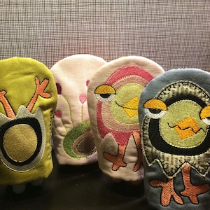 以下が含まれることがあります： 鳥の形をしたカラフルな手袋人形が4つ。人形は布製で、刺繍が施されています。人形はすべて異なる色で、異なる表情をしています。