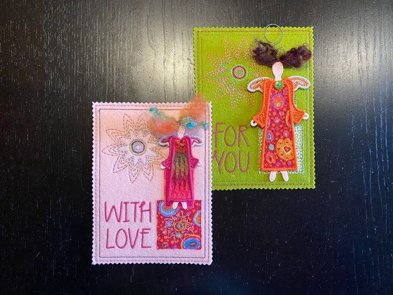 Puede incluir: Dos tarjetas de fieltro hechas a mano con &aacute;ngeles bordados y dise&ntilde;os florales. La tarjeta rosa dice "With Love" y la tarjeta verde dice "For You".