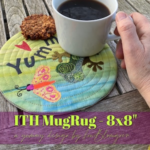 May include: A round, quilted mug rug with a butterfly and frog design. The rug is approximately 8x8 inches and features the word "Yum" with a red heart. A white mug of coffee and a cookie are on the wooden surface.