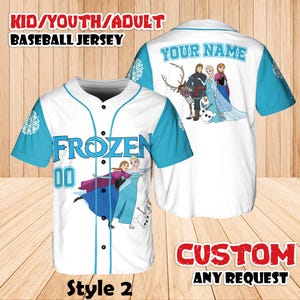 Puede incluir: Camiseta de b&eacute;isbol blanca con mangas y detalles en azul claro. La parte delantera presenta la palabra "FROZEN" y el n&uacute;mero "00", junto con im&aacute;genes de personajes. La parte trasera tiene el texto "YOUR NAME" y m&aacute;s im&aacute;genes de personajes. La camiseta est&aacute; etiquetada como "Style 2".