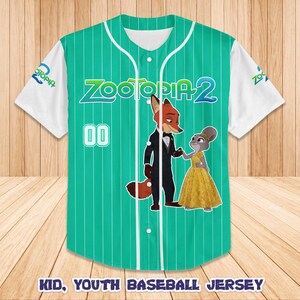 May include: A green and white baseball jersey featuring the characters Nick Wilde and Judy Hopps from Zootopia 2. The jersey has vertical stripes, the number 00, and the text "Zootopia 2". The sleeves are white.