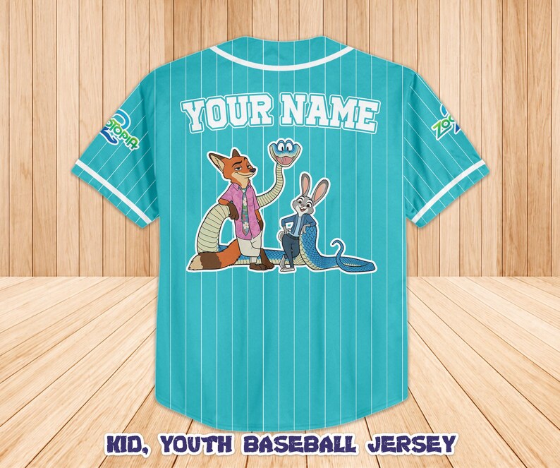Op de afbeelding: Turquoise honkbalshirt met witte krijtstrepen, met stripfiguren en de tekst "YOUR NAME" op de rug. De trui heeft witte biezen op de kraag en mouwen, en de tekst "KID, YOUTH BASEBALL JERSEY" staat onderaan.
