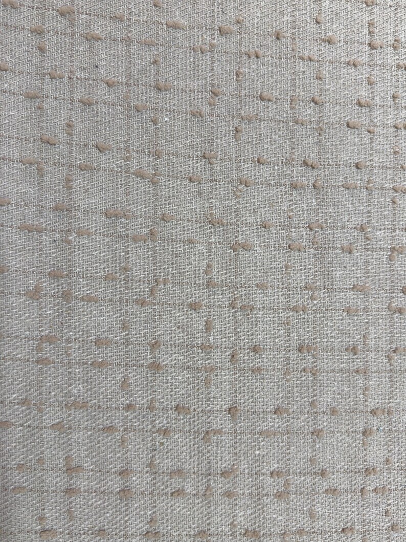 May include: A light gray fabric featuring a grid pattern formed by thin, darker gray lines. The intersection points of the grid are accented with small, raised, textured tufts of light brown thread, creating a subtle, tactile, and repeating design.