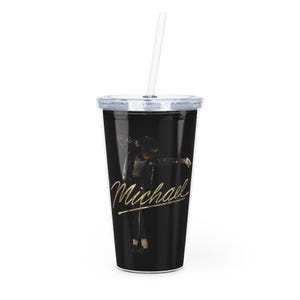 Könnte beinhalten: Ein schwarzer Becher mit einem durchsichtigen Deckel und Strohhalm. Der Becher zeigt ein goldenes Bild von Michael Jackson und seine Unterschrift in goldener Schrift. Der Becher ist für kalte Getränke konzipiert.