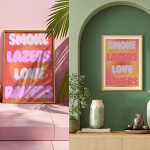 Puede incluir: Una impresión artística enmarcada con las palabras "SMOKE LAZERS LOVE RAVERS" en una fuente de burbujas. El fondo es un degradado de naranja, rosa y amarillo. El marco es dorado. La impresión se muestra sobre una superficie rosa y una pared verde.