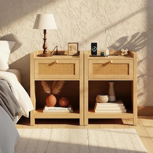 May include: Two light wood nightstands with woven drawer fronts. Each nightstand has a lamp, decorative items, and a charging station on top. A bed with white bedding is visible on the left. A monstera plant is on the right.