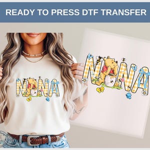 May include: A beige t-shirt with the word "NANA" in a yellow and white checkered pattern, featuring a Winnie the Pooh graphic. The design includes bees, butterflies, and flowers. The text "READY TO PRESS DTF TRANSFER" is at the top.