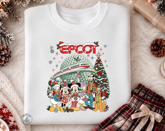 May include: A white crewneck sweatshirt featuring a colorful graphic print of Disney characters including Mickey, Minnie, Donald, Daisy, Goofy, and Pluto in holiday attire, with the text EPCOT, a monorail, and a Christmas tree in the background.